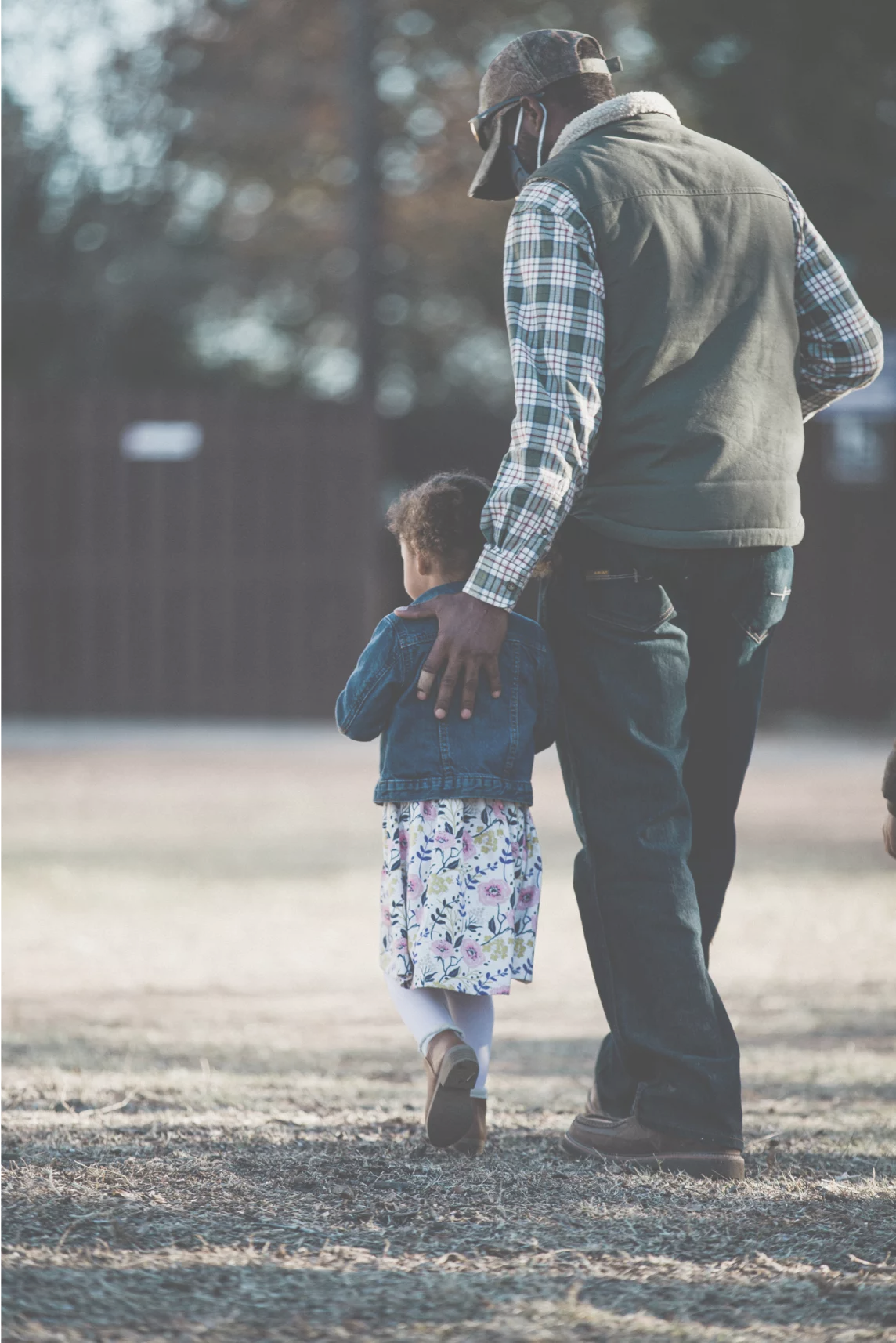 Black man walking with a young girl in a field